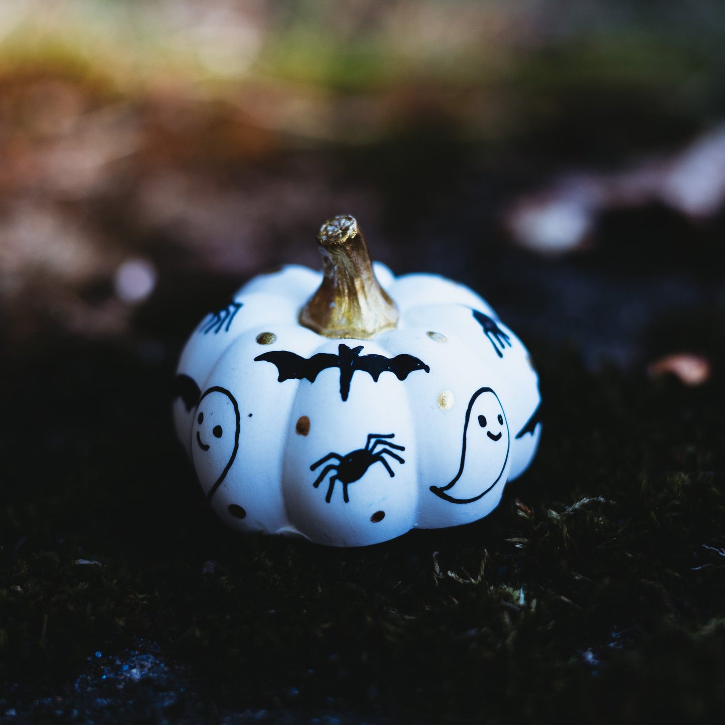 Small white pumpkin with Halloween drawings on a dark background