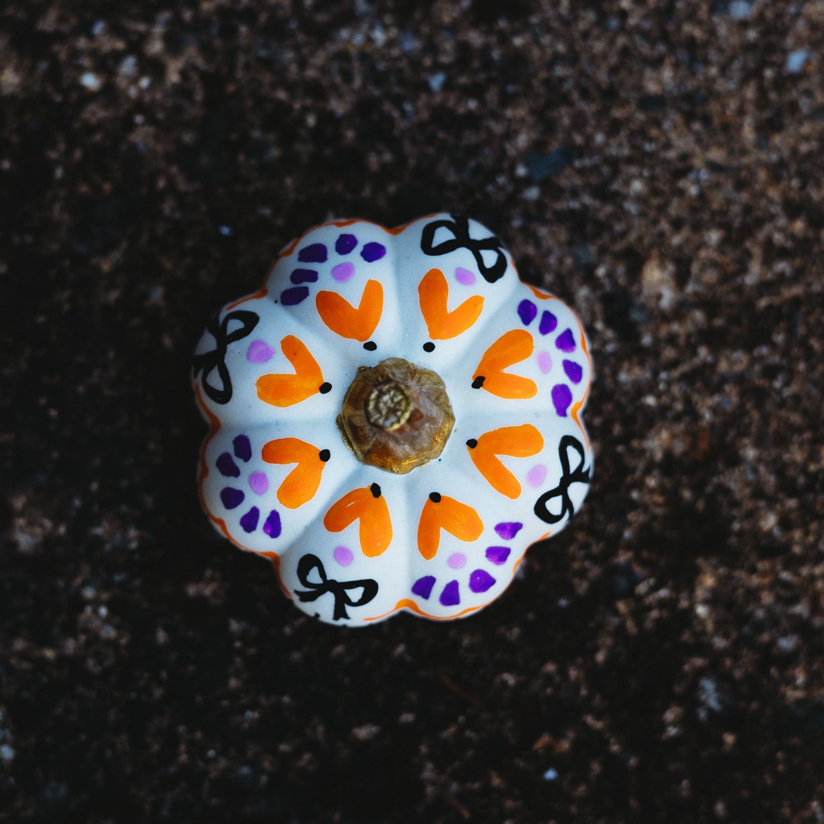 Decorative pumpkin with a colorful pattern on a dark surface