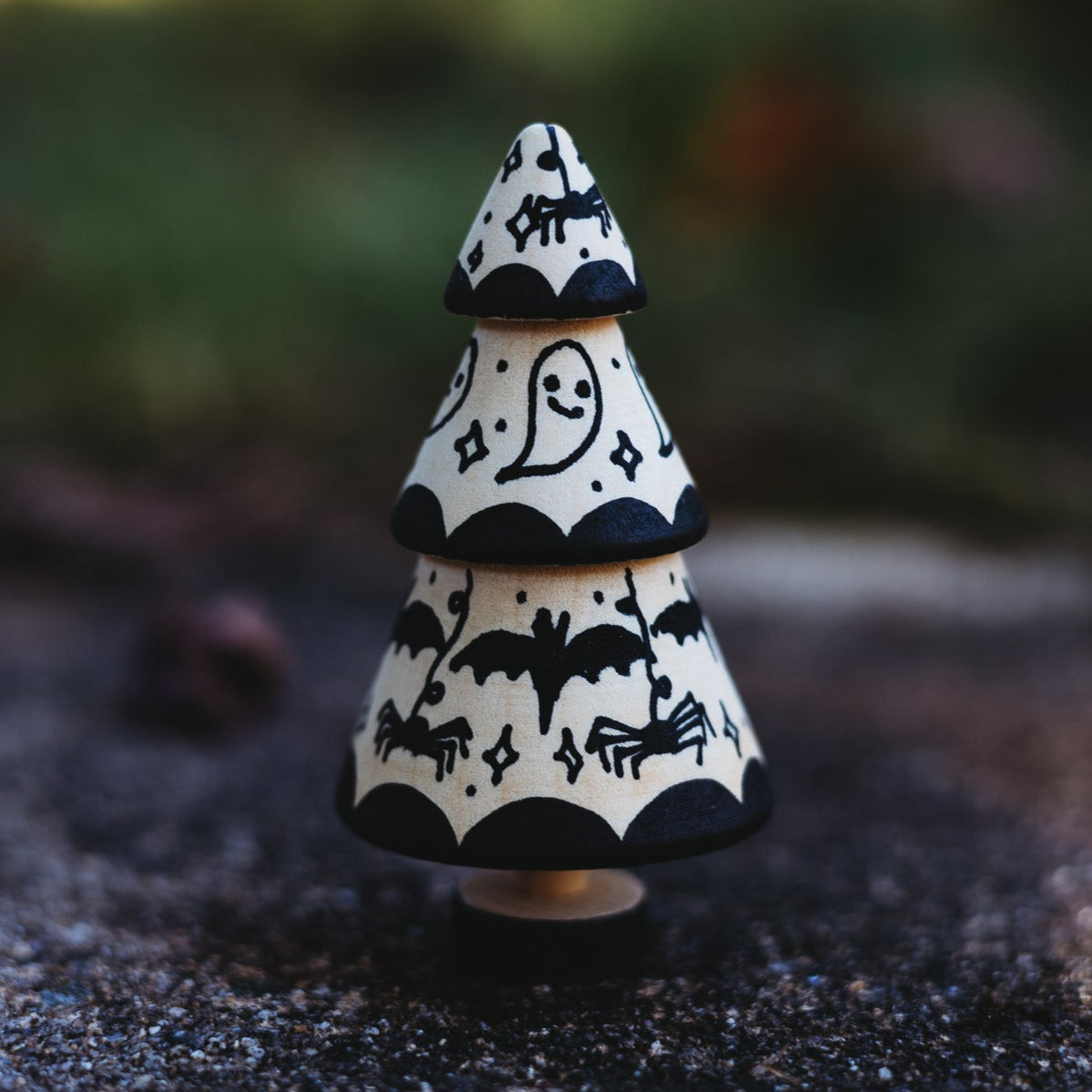 Decorative black and white tree-shaped object on a dark surface with a blurred natural background