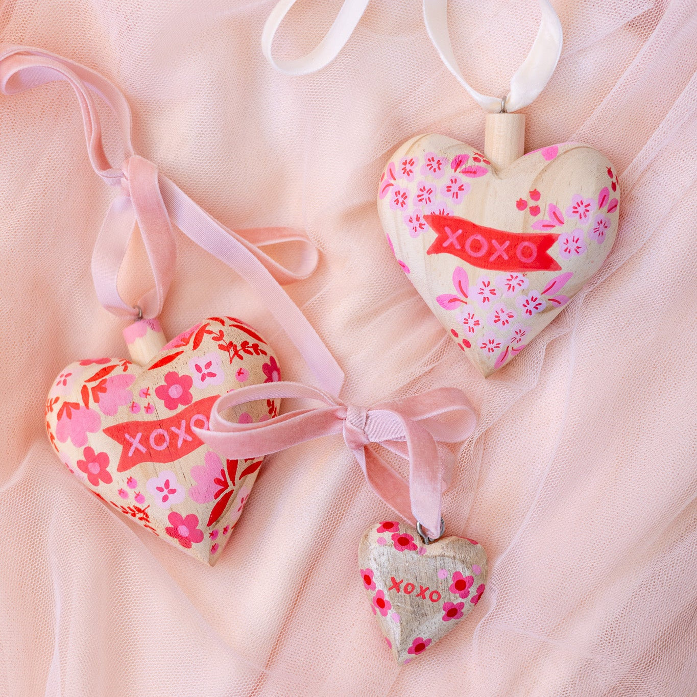 Heart-shaped decorations with 'XOXO' text on a soft pink background