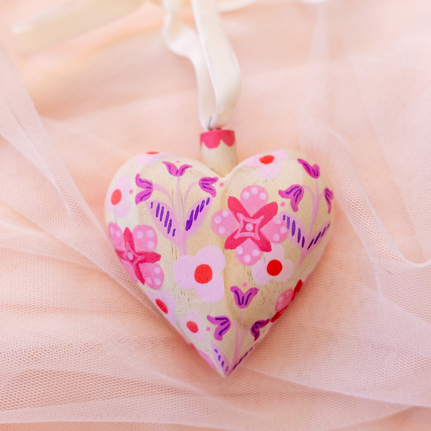 Heart-shaped pendant with floral patterns on a soft pink background