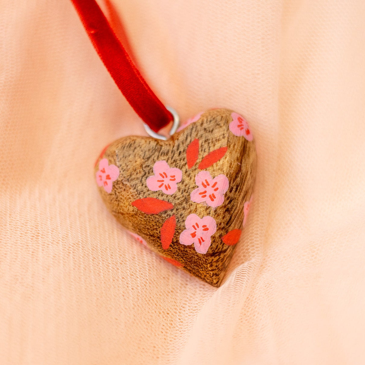 Heart-shaped pendant with floral design on a soft fabric background