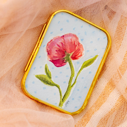 Decorative gold frame with a pink peony flower painting and a red ribbon on a sheer fabric background