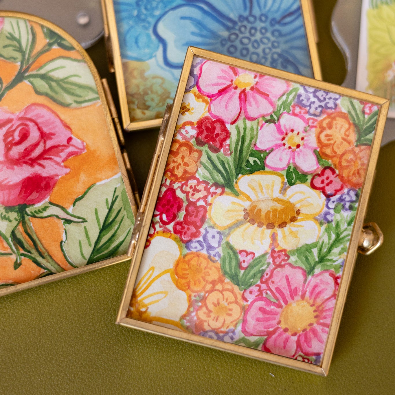 Decorative gold frames with floral paintings on a desk