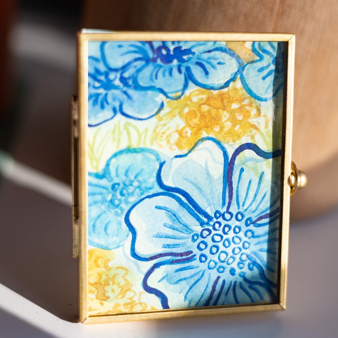 Decorative gold frame with floral painting on a desk
