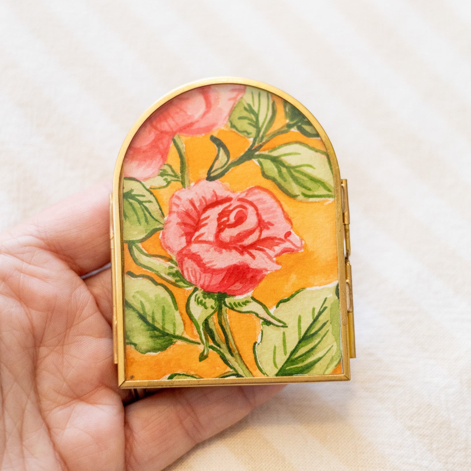 Decorative arch frame with floral painting in a hand