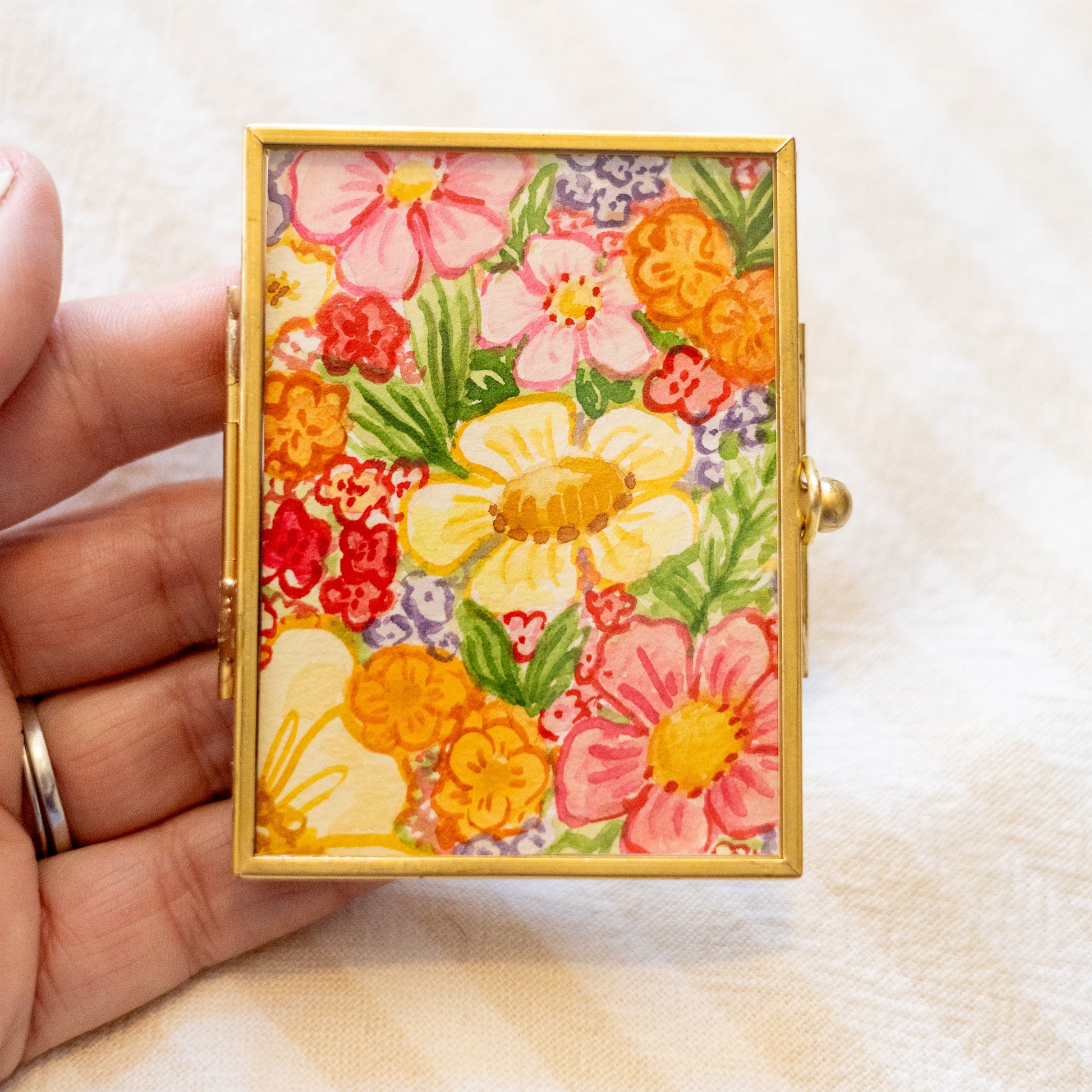 Decorative gold frame with floral painting in a hand